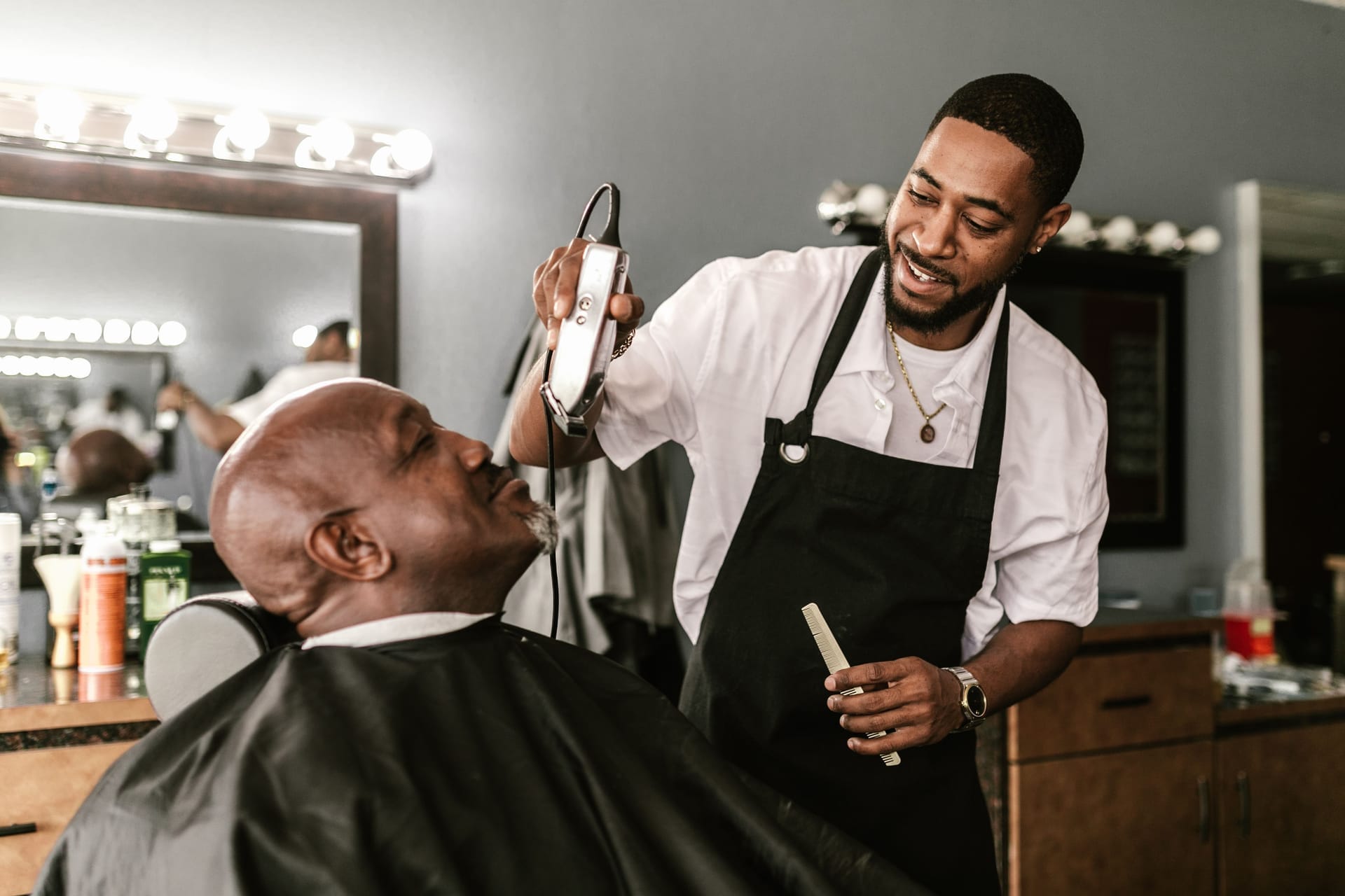Barber smiling while trimming a client's hair in a modern barbershop