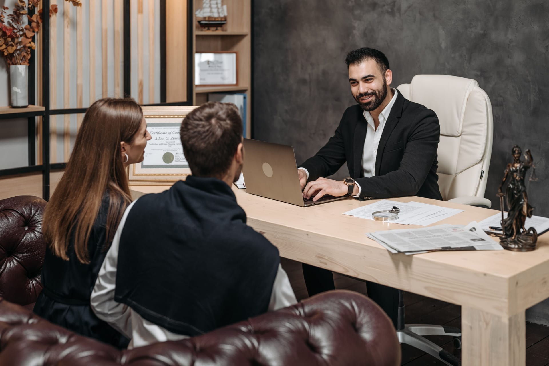 Attorney at his desk in a modern law office, consulting a couple seated across from him
