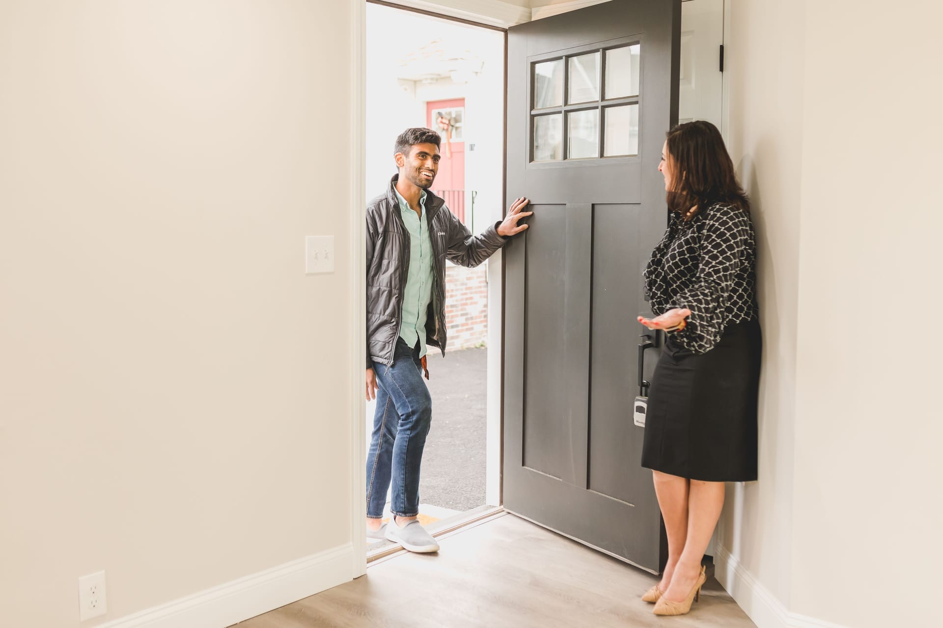 Real estate agent welcoming a young buyer at the front door of a bright new home